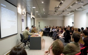 Fotografia colorida de um evento do Acervo no auditório da Fundação FHC. À esquerda, atrás de uma mesa de madeira, os palestrantes. Todos estão sentados. À direita, a plateia.