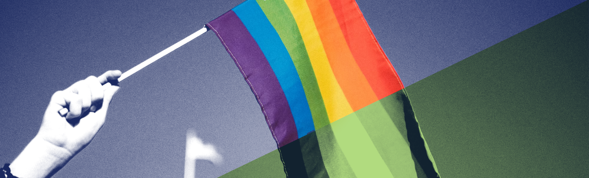 Fotografia que mostra uma mão humana segurando uma bandeira do movimento LGBT+. Há um leve filtro azul e verde sobre a foto.