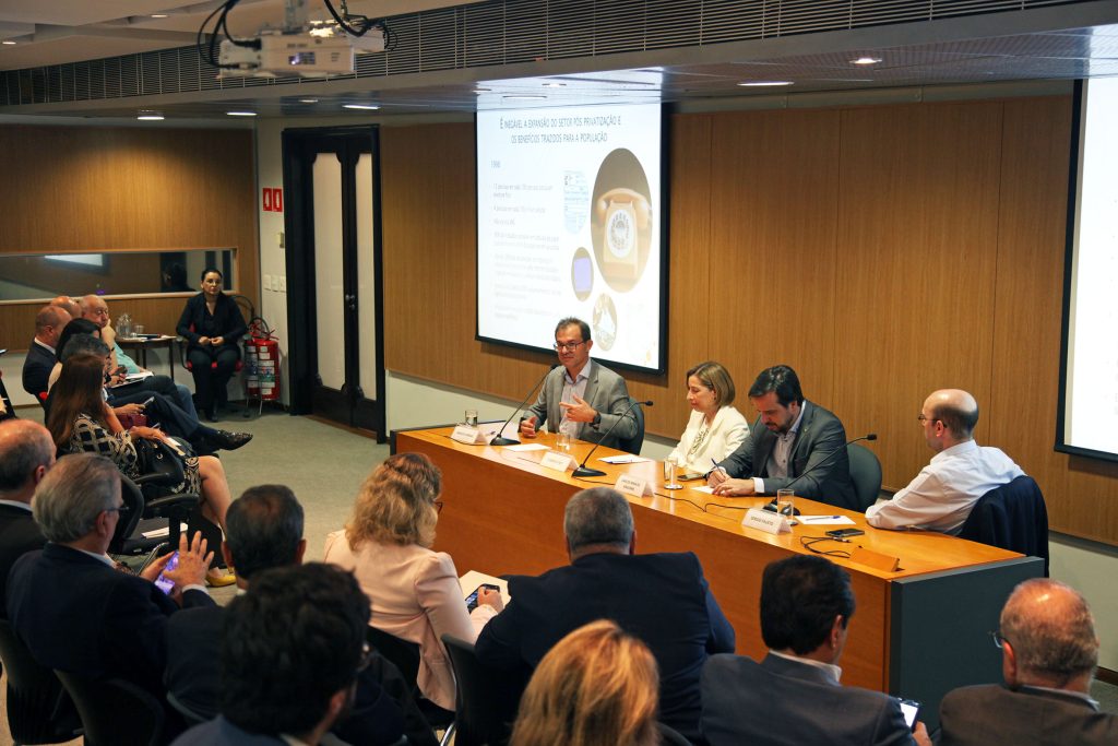 Fotografia colorida de um debate no auditório da Fundação FHC. À esquerda, a plateia. À direita, os palestrantes. Todos estão sentados atrás de uma mesa de madeira.