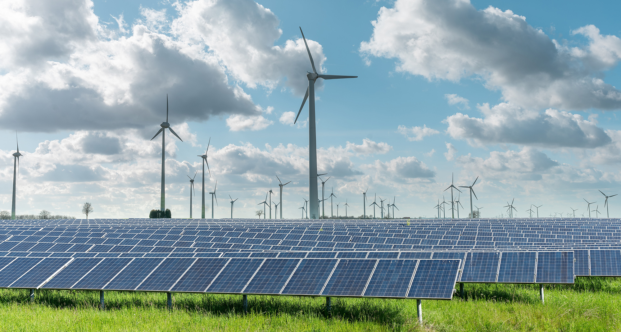 Fotografia colorida de painéis solares e hélices de energia éolica.