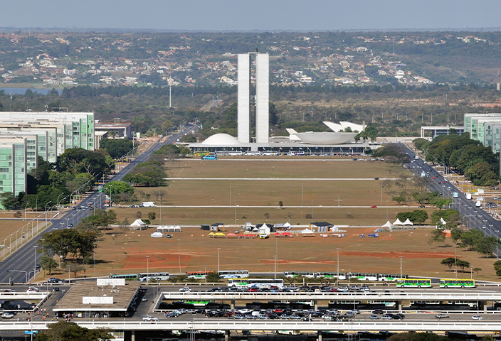 Fotografia colorida que mostra a Esplanada dos Ministérios, em Brasília. À esquerda e à direita, os prédios dos ministérios. Ao centro e ao fundo, o prédio do Congresso Nacional.